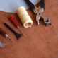 Leather crafting tools and waxed thread on suede hide