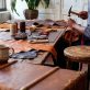 Leather craftsman working at rustic workshop table with tools